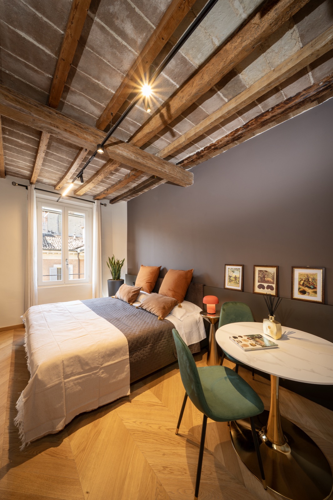 Il letto con i cuscini color terracotta e la pianta accanto