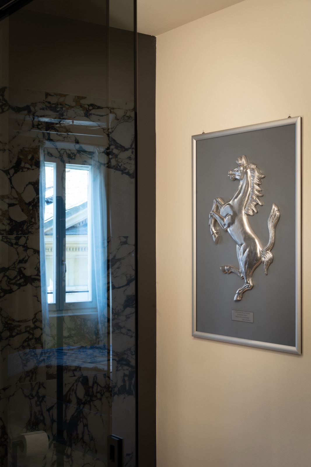 Il quadro del cavallino rampante riflesso nel vetro della doccia