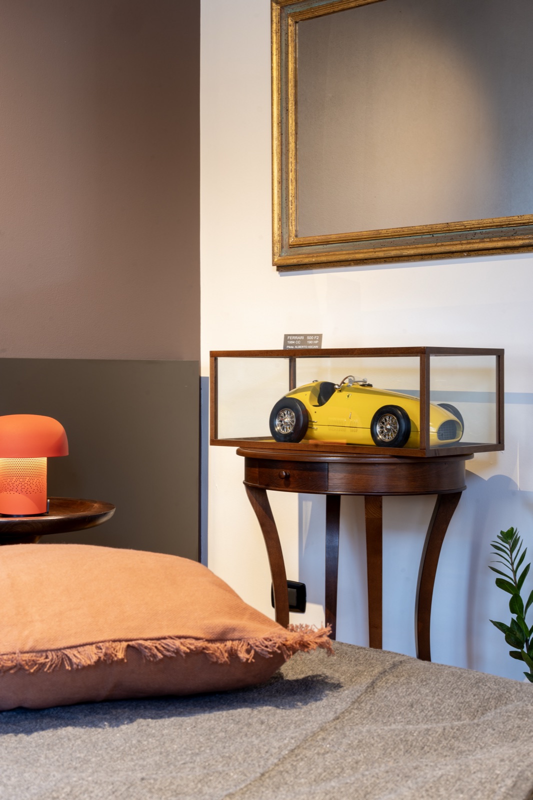 Il modellino in teca accanto al letto, con i cuscini in primo piano