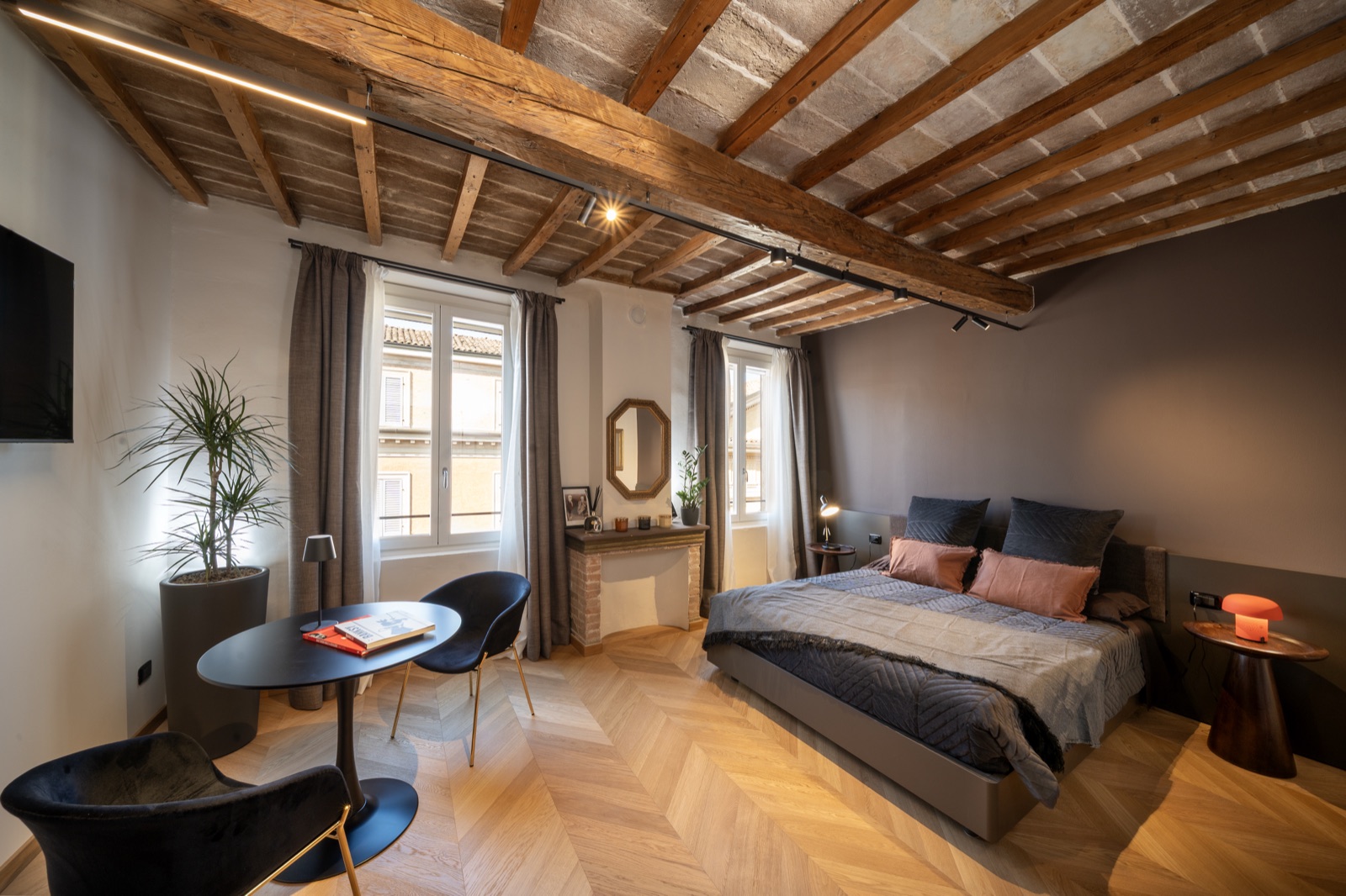 La camera vista dalla finestra, con il parquet a spina e il soffitto travato